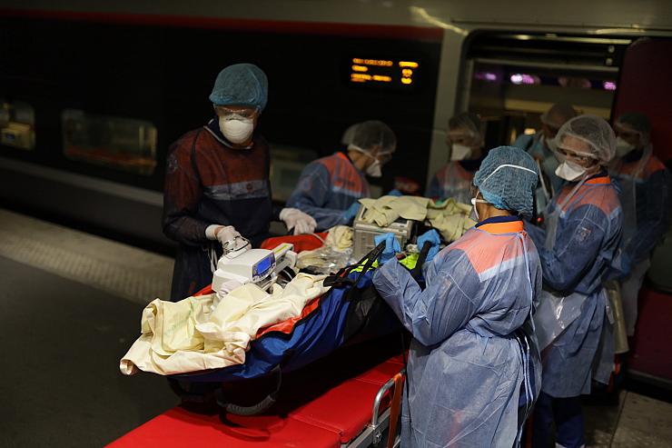 Mitja dotzena de socorristes vestits amb EPI COVID traslladen un pacient crític empaquetat en un sac de buit des d'una llitera d'ambulància a l'interior d'un TGV