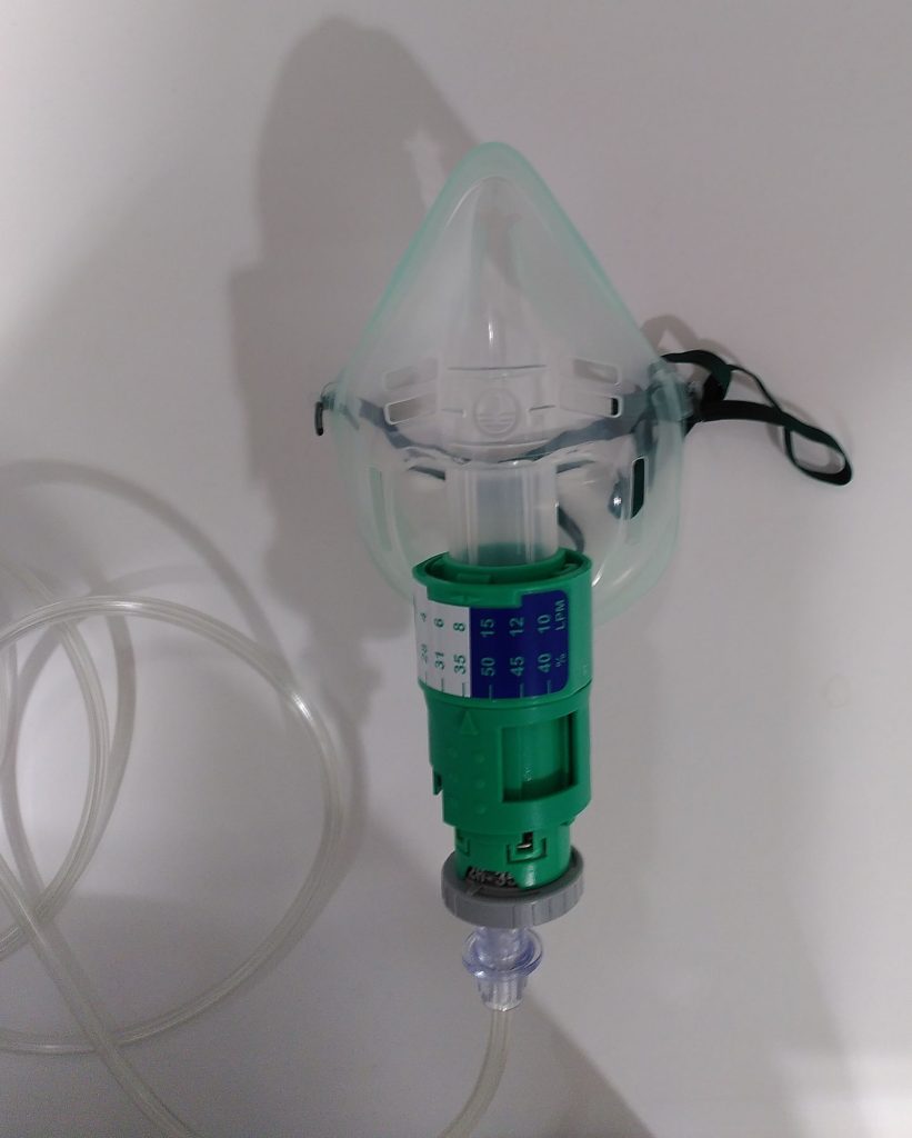 Mascareta venturi d'administració d'oxigen. Hi ha una màscara de plàstic flexible verd-transparent, amb una veta elàstica verda que es fixa als dos laterals de la màscara. Per davant la part del mentó de la màscara en surt el tub rodó on encaixa el dispositiu Venturi, un cilindre verd compost de dues peces. A la superior hi ha la retolació del percentatge d'oxigen i flux que corresponen a cada marca. La part inferior és un cilindre que va una mica per sobre del cos de l'anterior, té un quadrat foradat en un lateral i una fletxa que assenyala les marques superiors. Aquest mecanisme es belluga ajustant la fletxa amb les marques del cilindre superior, fent més gran o més petit l'orifici resultant. A la part inferior d'aquest cilindre s'hi connecta un tub que es connectaria amb una font d'oxigen